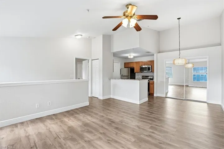 Unfurnished living room featuring a high ceiling, a ceiling fan, and light wood-style flooring