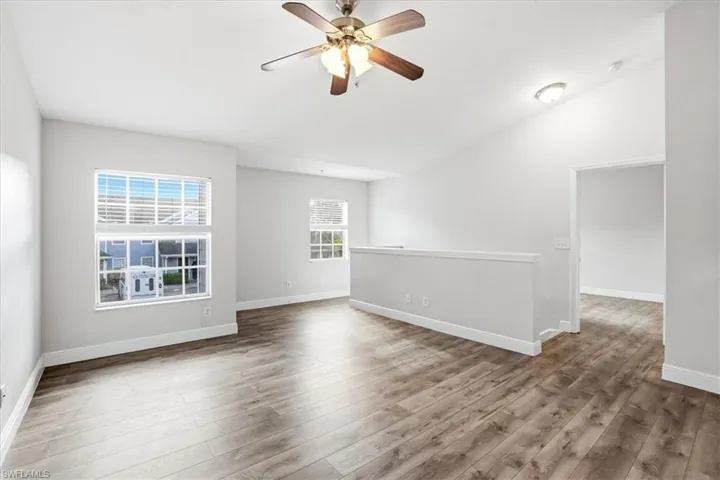 Spare room with a ceiling fan, wood finished floors, and lofted ceiling