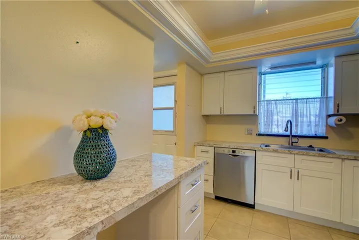 Kitchen featuring dishwasher, white cabinetry, healthy amount of natural light, light countertops, and ornamental molding, ceiling fan