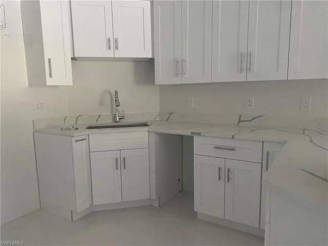 Kitchen featuring light stone countertops and white cabinets