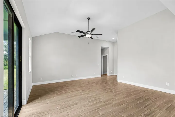 Spare room with lofted ceiling, wood tiled floors, and ceiling fan