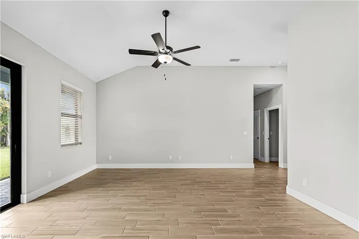 Empty room featuring lofted ceiling, wood tiled floors, and a ceiling fan