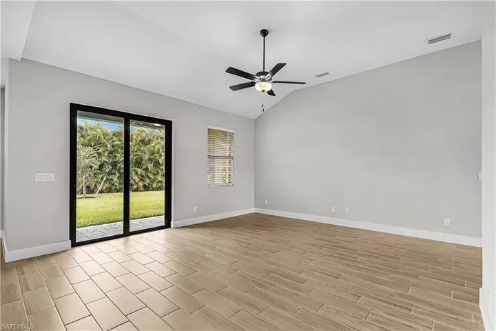 Unfurnished room with vaulted ceiling, wood finish floors, and a ceiling fan