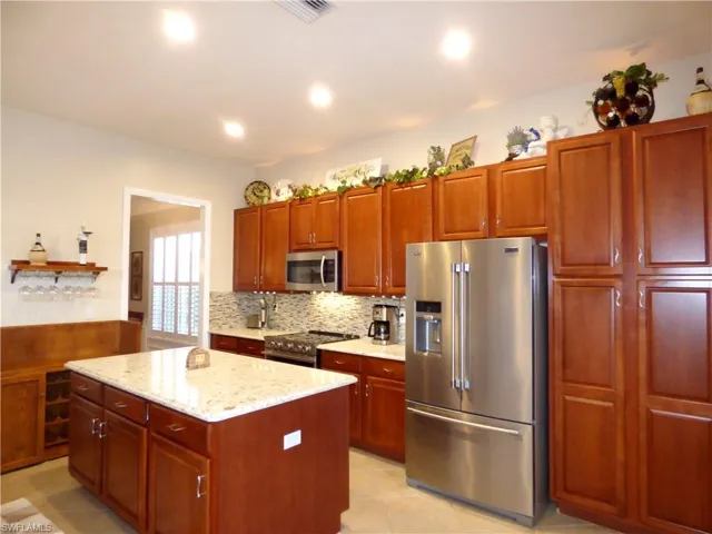 Kitchen with quartz countertops, tile flooring, backsplash, a center island, and stainless steel appliances