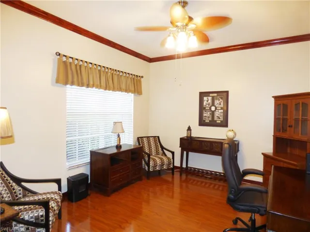 Home office with crown molding, wood flooring, and ceiling fan
