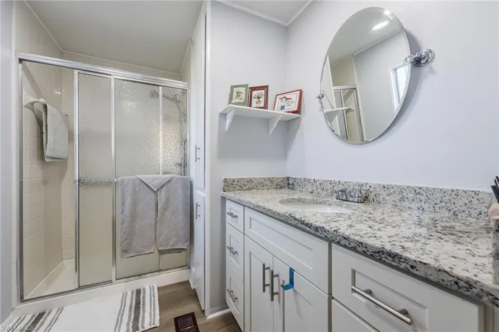 Bathroom featuring vanity, a stall shower, and wood finished floors