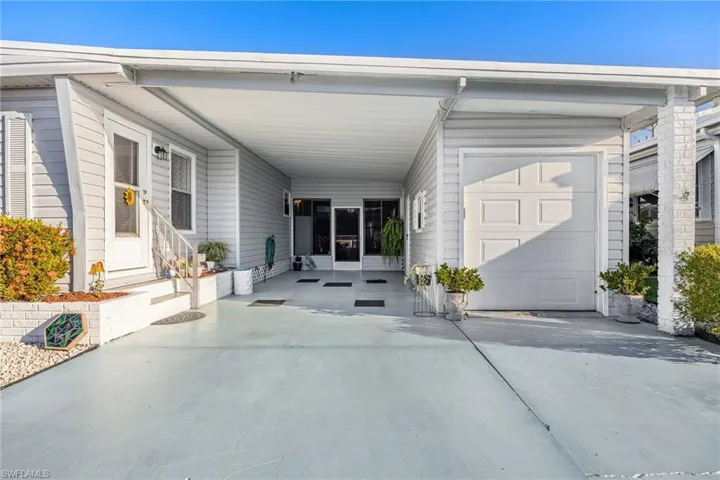 View of exterior entry with a carport, driveway, and a patio