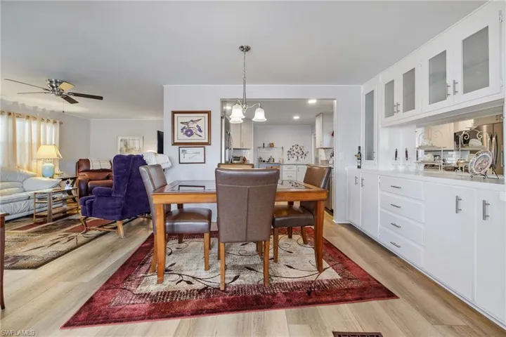 Dining room with light wood finished floors, ceiling fan, and a chandelier