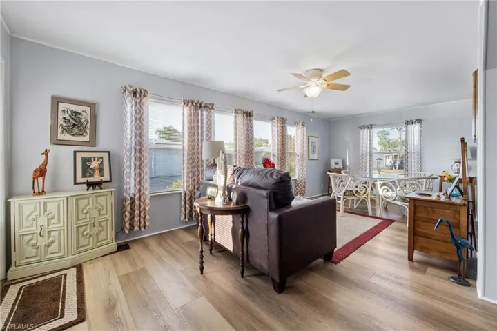 Living room with healthy amount of natural light, light wood-style floors, and a ceiling fan