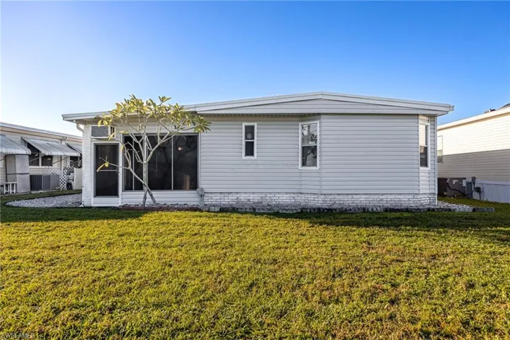 Back of house with a lawn and a sunroom