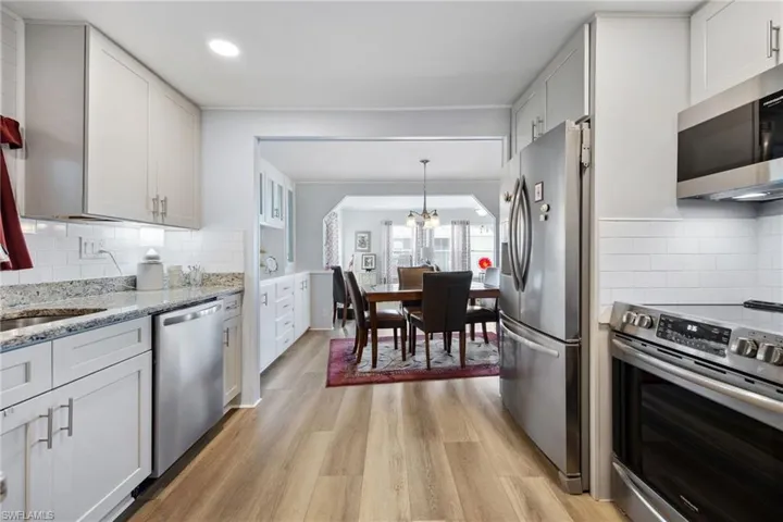 Kitchen featuring tasteful backsplash, stainless steel appliances, light wood-style floors, and white cabinets