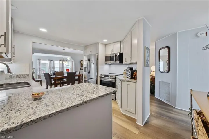 Kitchen featuring hanging light fixtures, light stone countertops, appliances with stainless steel finishes, a chandelier, and recessed lighting