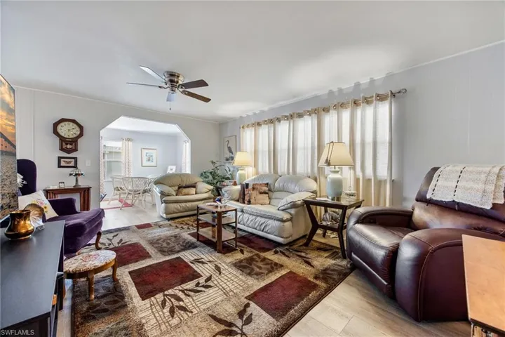 Living room featuring wood finished floors, arched walkways, and ceiling fan