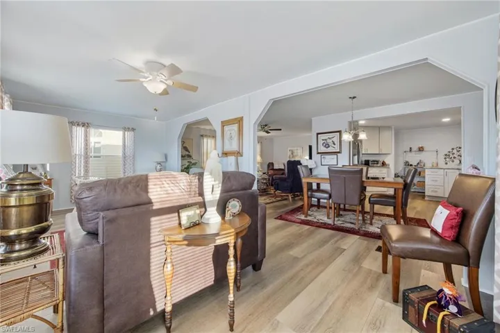 Living room with light wood-type flooring, a chandelier, a ceiling fan, and arched walkways