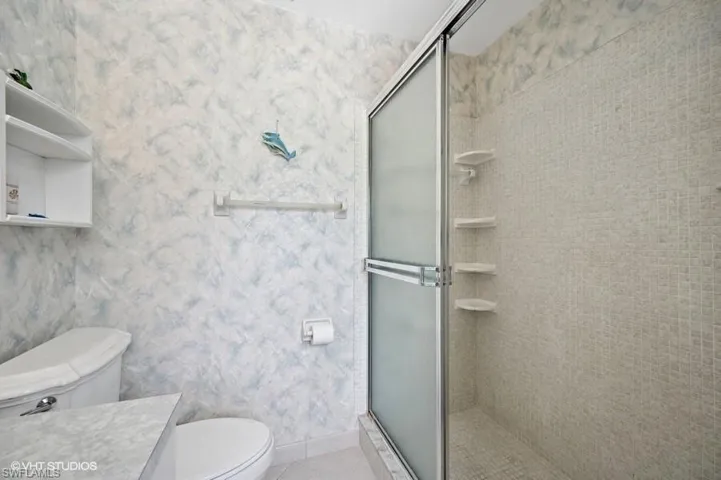 Bathroom with toilet, vanity, tile patterned floors, and a shower stall