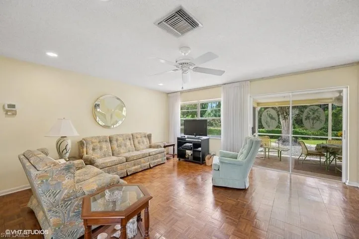 Living room with a textured ceiling, baseboards, ceiling fan, and visible vents