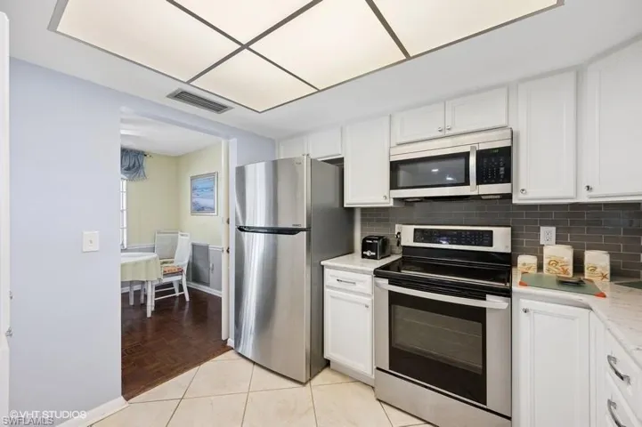 Kitchen featuring light countertops, stainless steel appliances, white cabinets, and tasteful backsplash