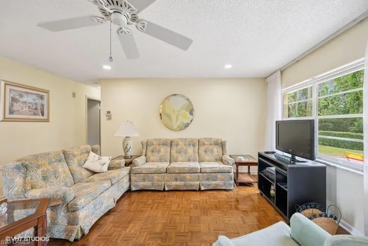 Living area with a ceiling fan, recessed lighting, and a textured ceiling