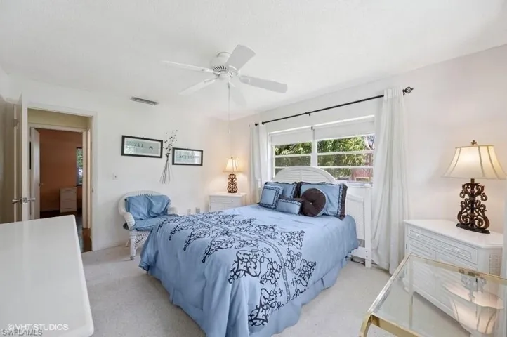 Bedroom featuring a textured ceiling, visible vents, ceiling fan, and light carpet