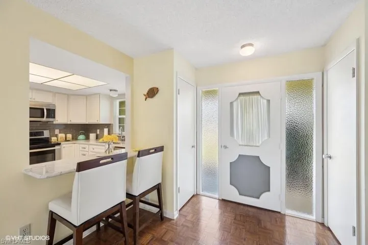 Kitchen featuring a textured ceiling, a peninsula, a breakfast bar, tasteful backsplash, and appliances with stainless steel finishes