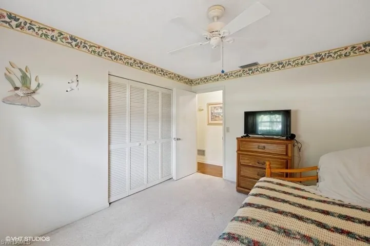 Carpeted bedroom featuring visible vents, a closet, and ceiling fan