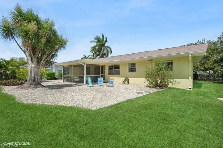 Rear view of house with stucco siding, a sunroom, and a yard