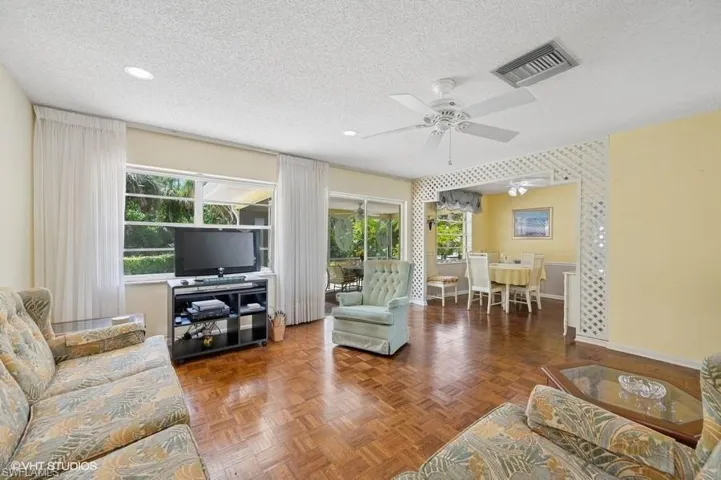 Living area featuring a ceiling fan, a textured ceiling, baseboards, visible vents, and recessed lighting