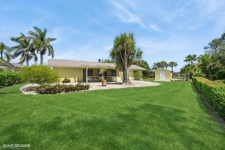 Rear view of property with a yard, stucco siding and a storage shed