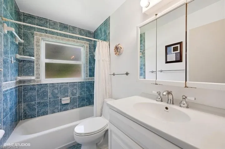 Bathroom featuring toilet, vanity, and shower / bath combination with curtain