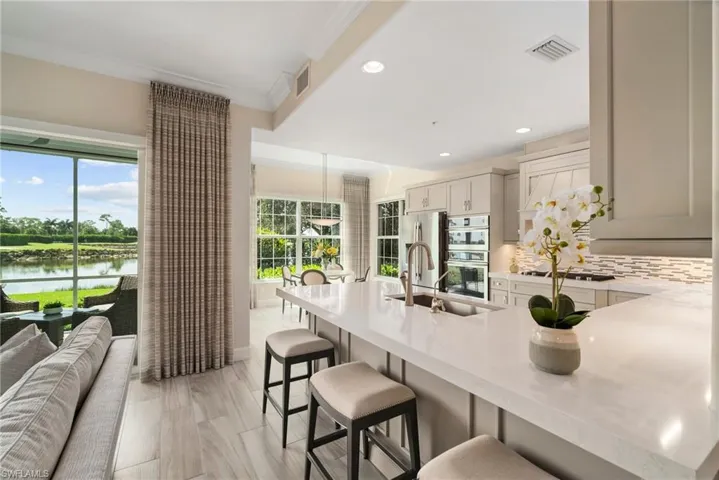Kitchen featuring sink, backsplash, a water view, a kitchen breakfast bar, and ornamental molding