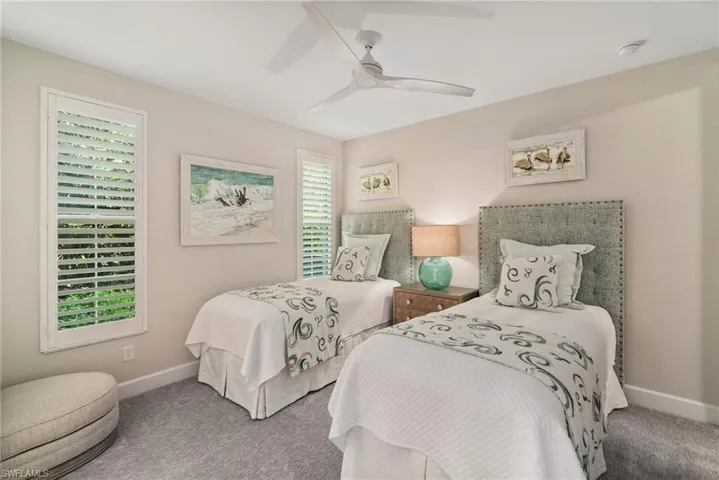 Carpeted bedroom with multiple windows and ceiling fan