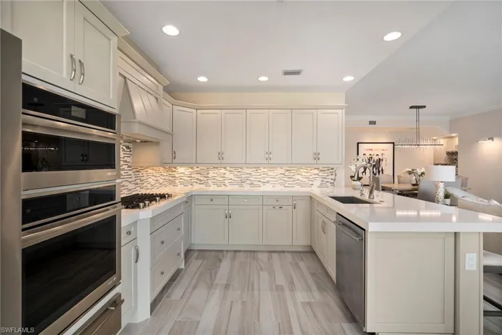 Kitchen featuring stainless steel appliances, sink, kitchen peninsula, backsplash, and crown molding