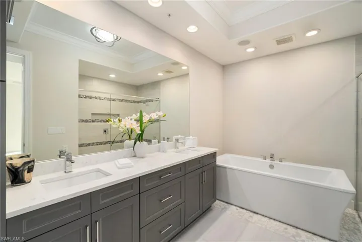 Bathroom with a tub, tile patterned floors, crown molding, and double vanity