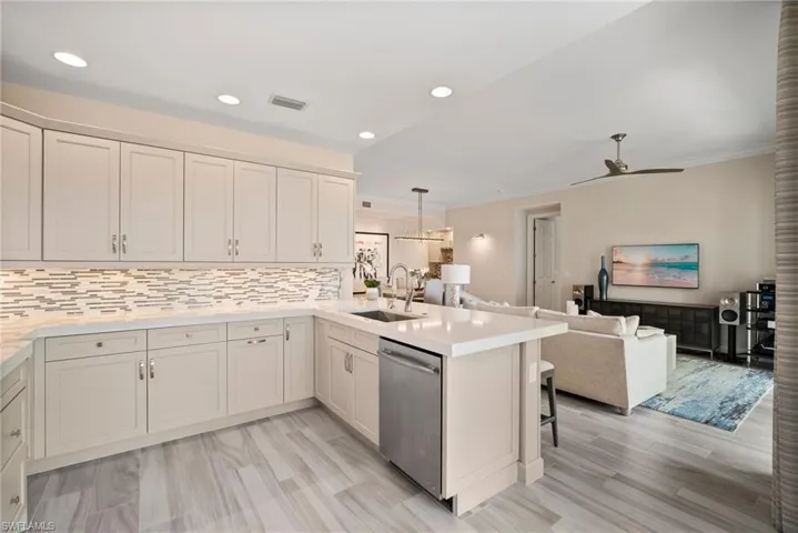 Kitchen with stainless steel dishwasher, sink, kitchen peninsula, and tasteful backsplash
