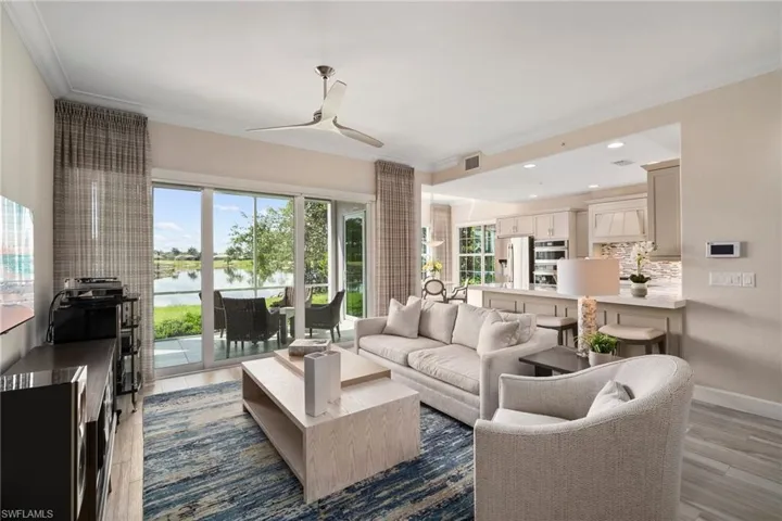 Living room featuring a water view, ceiling fan, wood-type flooring, and ornamental molding