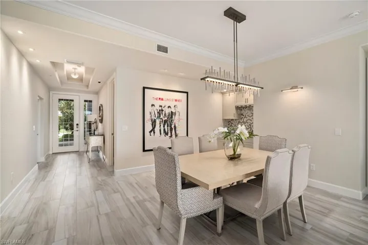 Dining space with crown molding, french doors, a tray ceiling, and light hardwood / wood-style flooring