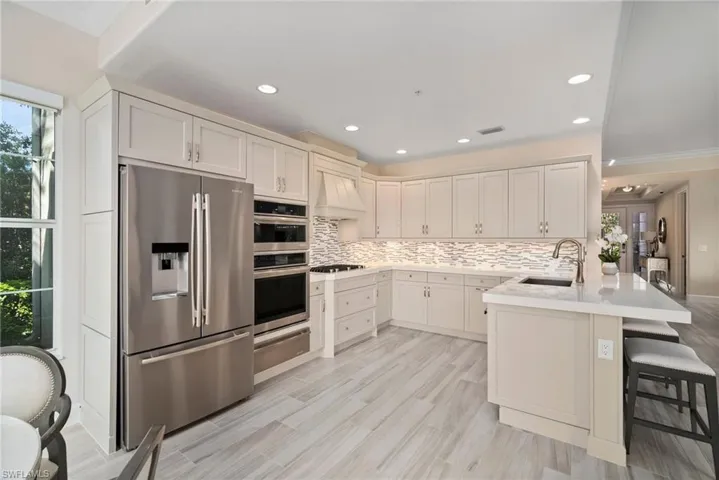 Kitchen with crown molding, sink, appliances with stainless steel finishes, a kitchen breakfast bar, and backsplash