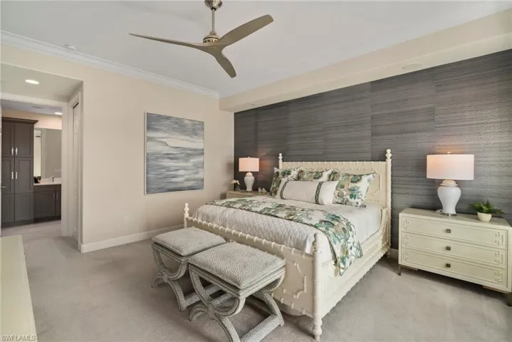 Carpeted bedroom featuring ornamental molding, ensuite bathroom, and ceiling fan