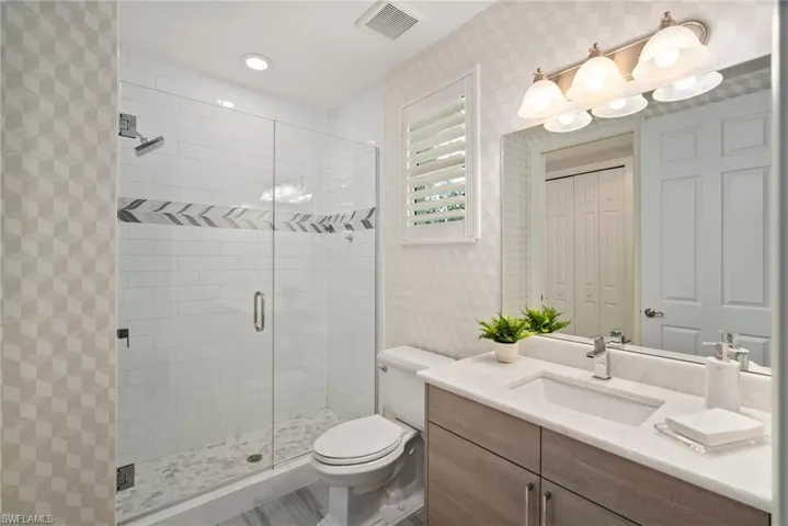 Bathroom featuring vanity, a shower with door, and toilet