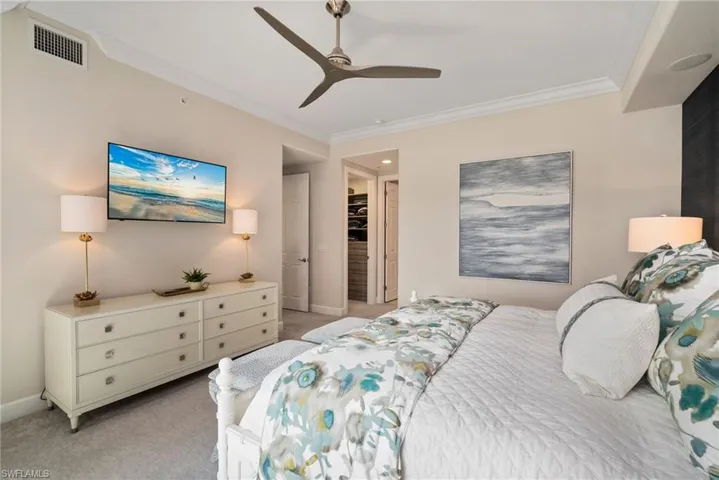 Carpeted bedroom with crown molding, a walk in closet, ceiling fan, and a closet