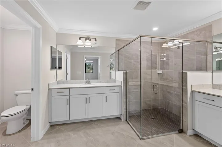 Bathroom featuring crown molding, vanity, and a shower stall