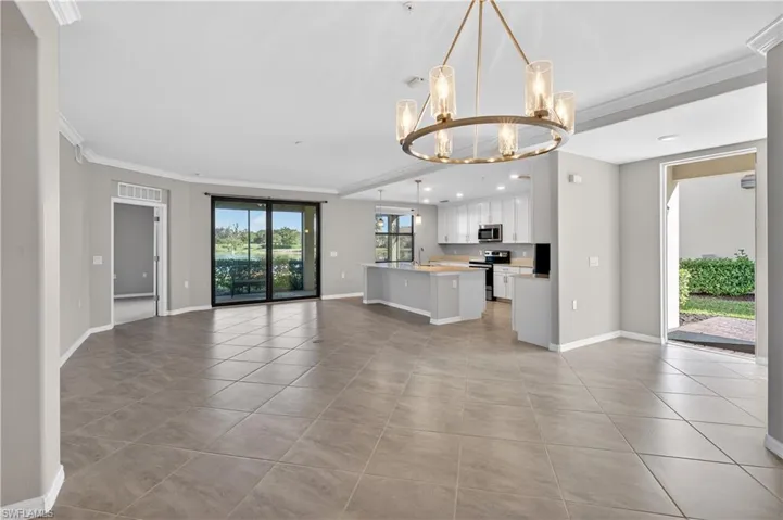 Unfurnished living room featuring crown molding, a chandelier, light tile patterned flooring, and recessed lighting