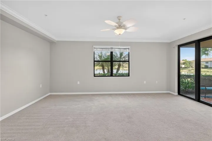 Spare room featuring light colored carpet, ornamental molding, and a ceiling fan