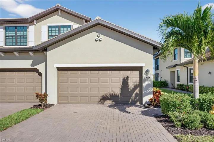 View of front of house with stucco siding, a garage, and decorative driveway