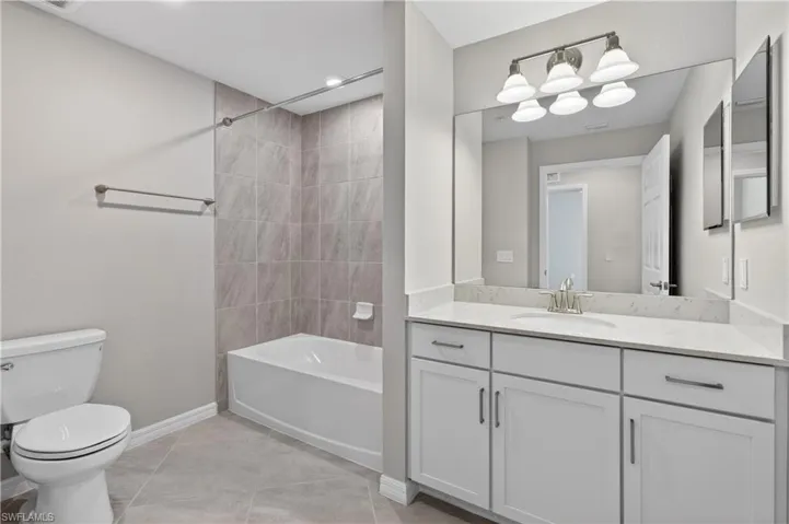 Bathroom with washtub / shower combination, vanity, and light tile patterned floors