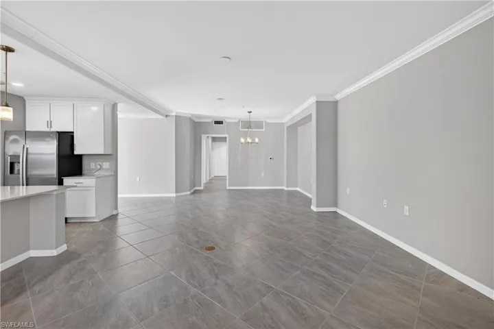 Unfurnished living room with ornamental molding, a chandelier, and dark tile patterned floors