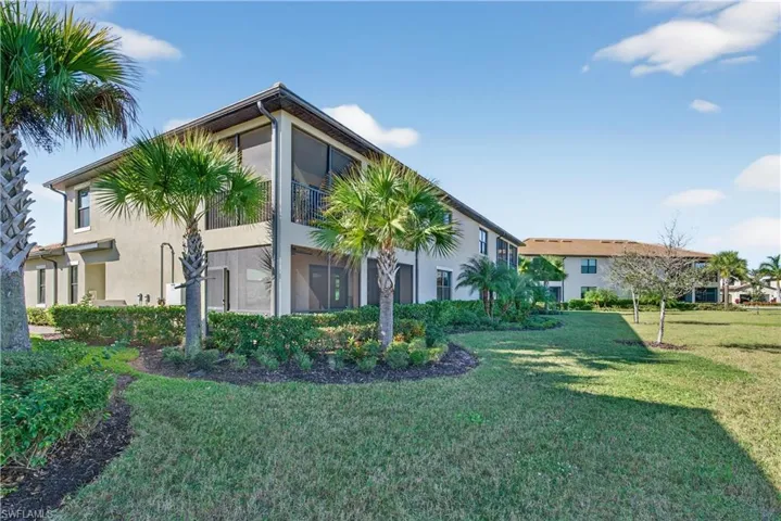 View of side of home with stucco siding, a lawn, and a sunroom
