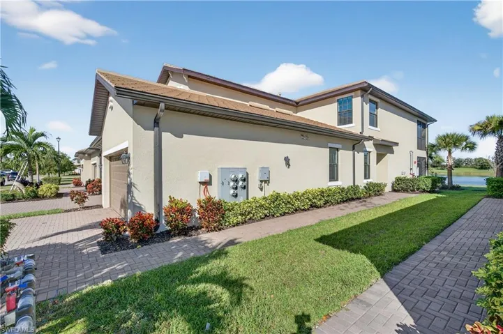 View of side of home featuring a yard, stucco siding, an attached garage, and decorative driveway