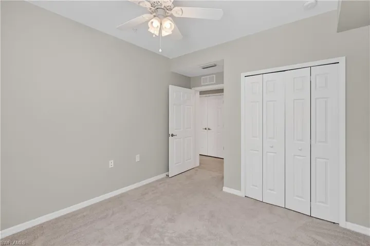 Unfurnished bedroom featuring light colored carpet, ceiling fan, and a closet