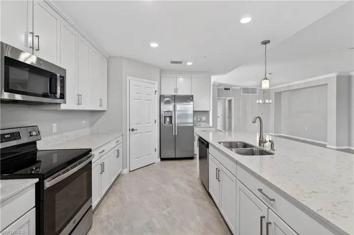 Kitchen featuring stainless steel appliances, pendant lighting, white cabinets, light stone counters, and recessed lighting